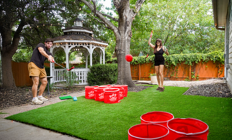 Full PopPong court in a backyard — two triangles of buckets facing off across the lawn
